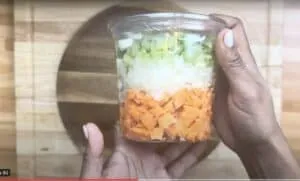 Chopped vegetables in a plastic container: carrots, onions, and celery. Perfect for soups and stews preparation.